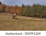 Tractor pulls the fallen tree. Working in the forest. Tractor is skidding cut trees out of the forest. Skidding timber.
