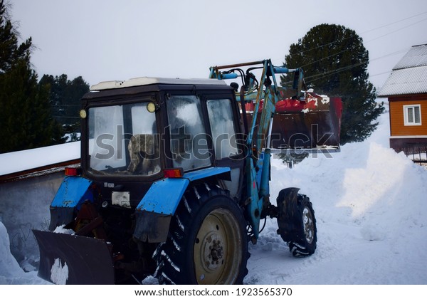 tractor removes snow\
in the yard, winter day