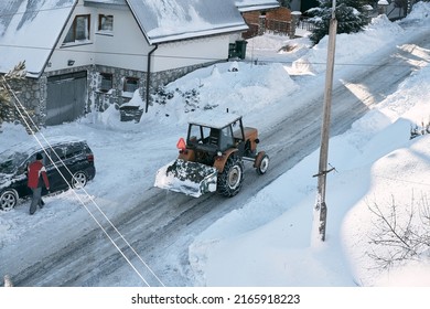 tractor removing snow in mountain suburban area. bulldozer is de-icing roads in countryside