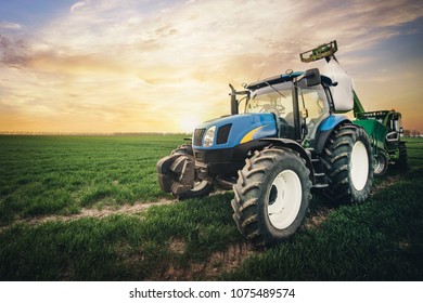 a tractor with a sack of fertilizer moves along the field in the spring - Shutterstock ID 1075489574