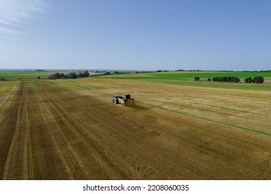 A Tractor Is Scattering Manure Over A Large Field From A Trailer Nearby. Soil Fertilization. Natural Fertilizer. Agriculture. View From Above.