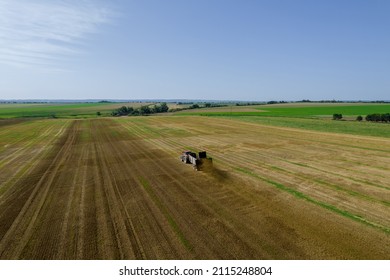 The tractor scatters manure on the field. Feeding the soil before harrowing. View from above. Agricultural work.