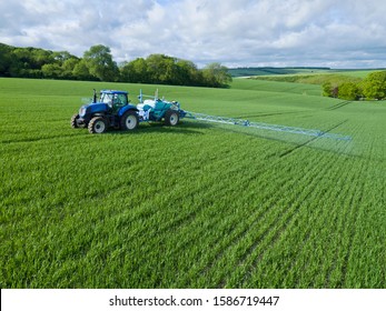 Tractor Spraying Crop In Green Farm Fields With Pesticide