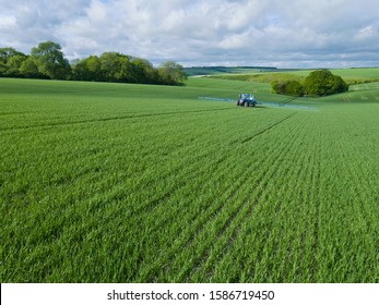 Tractor Spraying Crop In Green Farm Fields With Pesticide