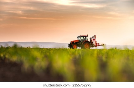 Tractor spraying pesticides on corn field  with sprayer at spring - Shutterstock ID 2155752295