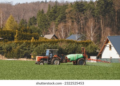 Tractor spraying pesticides on the field with sprayer at spring. agricultural fields in spring. concept of rural farm countryside - Shutterstock ID 2322525453