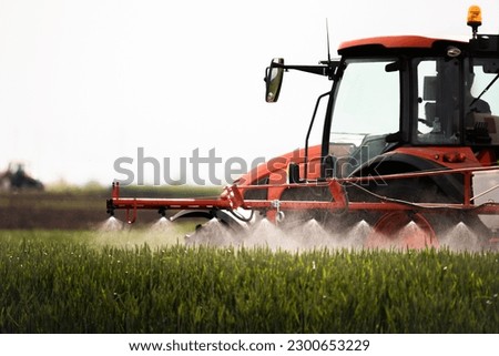 Tractor spraying pesticides over a green field