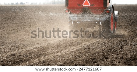 Tractor spreading artificial fertilizers  in field