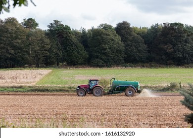 A Tractor Spreading Slurry, Fertilizer On The Field Ready To Plant New Crop