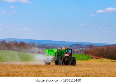 The tractor spreads granular fertilizer on a grass field. Agricultural work. Mineral fertilizers. Nitrate.