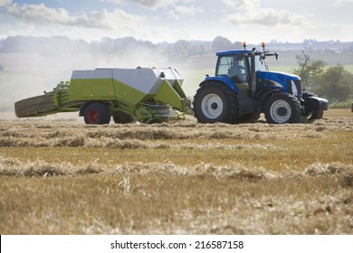 Tractor And Straw Baler In Sunny, Rural Field