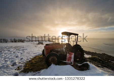 Tractor at sunrise on an icy lake
