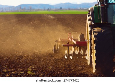 Tractor In Sunset Plowing The Field