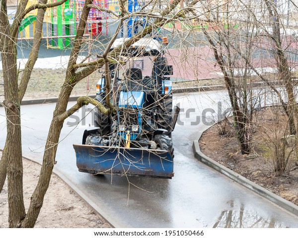 Tractor sweeping the\
street in the village\
