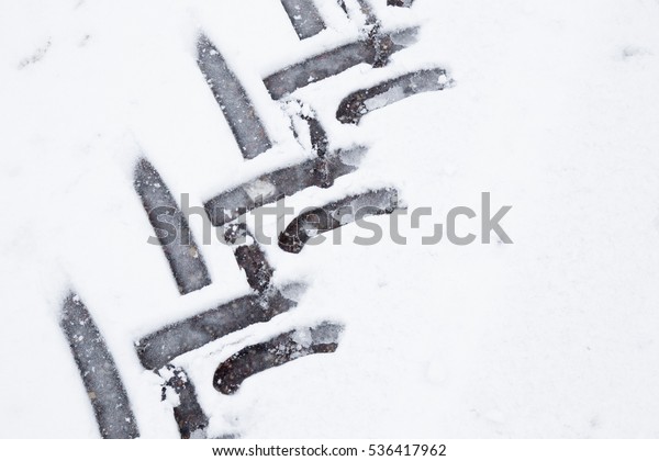 Tractor tire imprint in the\
wet, soft snow on the asphalt in winter day. Slippery road.\
Background.
