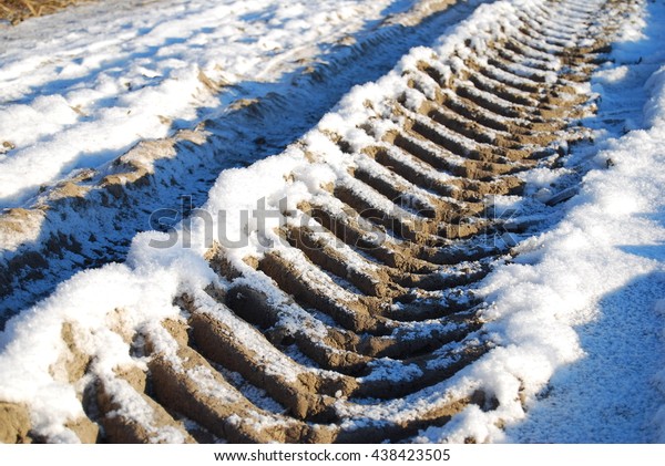 Tractor tire prints in winter. Large\
tractor tire prints in the forest during winter\
season