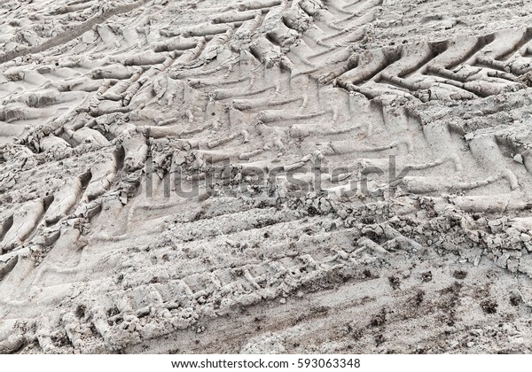 Tractor tire tracks\
pattern on gray ground, abstract transportation background photo\
with selective focus