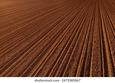 Tractor tire tread and tiller marks in plowed soil ground, aerial shot, high angle view - Powered by Shutterstock