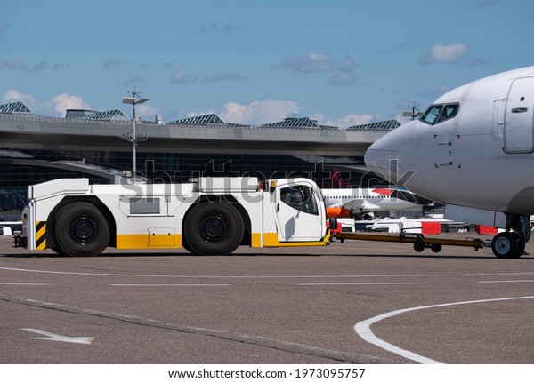 tractor tows\
an airplane to the airport parking\
lot