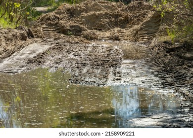 Tractor Tracks In The Mud. Large Dirty Puddle Filled The Hole After The Tractor. No Road. Ground Water.