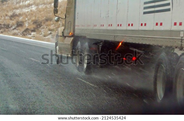 Tractor trailers drive cautiously on icy roads \
in Eastern Oregon..