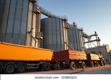 Tractor and Truck Beside Grain Silos. Commercial Steel Silos and Bins for Grain Storage.
Loading maize, wheat or soybean into the metal silos for storage after the harvest.