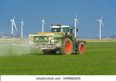 Tractor with two-disc fertilizer spreader on the cornfield while fertilizing