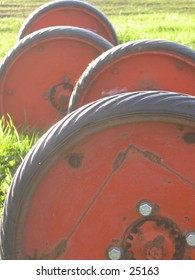 Tractor wheels sitting in the grass lit by a bright sun.