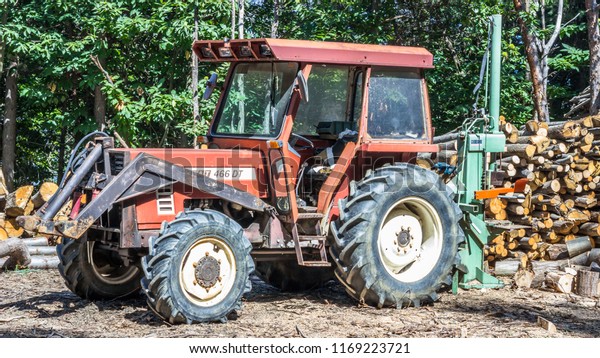 Tractor of Woodman in the Wood\
near a Pile of logs cut in Sassello,Italy-August\
2018