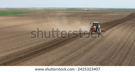 Tractor working in the field, preparing the land for planting,  working plowed field