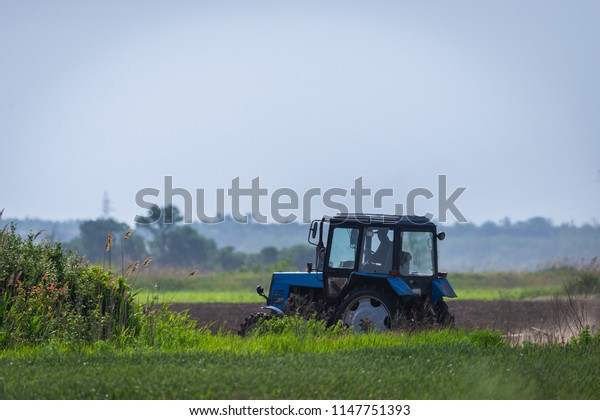 Tractor working\
on the farm, a modern agricultural transport, a farmer working in\
the field, fertile land, tractor on a sunset background,\
cultivation of land, agricultural\
machine