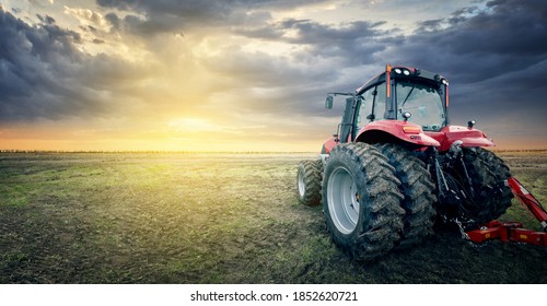 The tractor works in the field against the background of sunset. - Shutterstock ID 1852620721