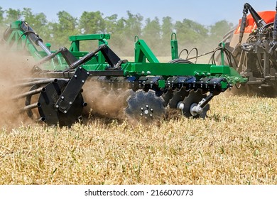 The tractor works in the field with a plow with a disc harrow. Seasonal tillage for subsequent sowing of grain. - Shutterstock ID 2166070773