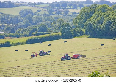 Tractors And Bale Wrapper Baling Hay In Field, Dorset, UK