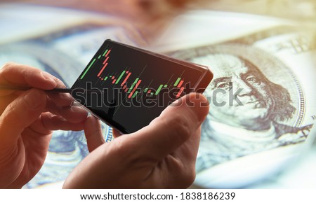 Trade. Analysis of exchange information. Profit from exchange operations. Bidding on the Internet. A person studies the chart of changes in quotes on a smartphone. Stock analysis. Exchange strategies.