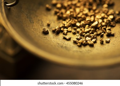 Trade and exchange. Weighing a gold nugget on a old brass scale dish.for trading. Shallow depth of filed.