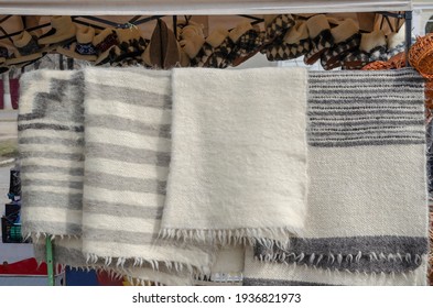 Trade In Natural Wool Products On The Local Market. Traditional Ukrainian Striped Blanket And Room Shoes Made Of Sheep's Wool. Street Trade. Spring Craft Fair.