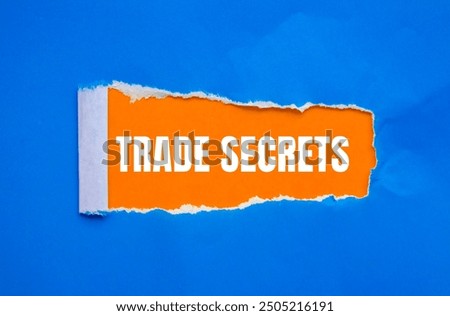 Trade secrets message written on ripped torn blue paper with orange background. Conceptual trade secrets symbol. Copy space.