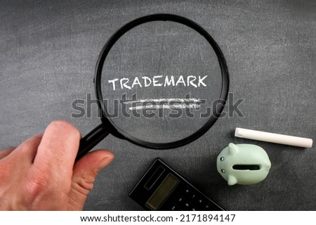 Trademark concept. Magnifying glass and text on a dark chalkboard.