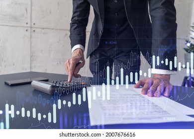 A Trader Computing Historic Data To Predict Stock Market Behavior. Internet Trading Concept. Forex And Financial Hologram Chart Over The Desk And Calculator.