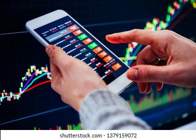 A trader or a financial analyst checking the recent stock exchange trends using the smartphone. - Shutterstock ID 1379159072