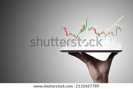 Trader holding Tablet and touching to technical graph chart  for analysis stock market data and speculator investment concept.