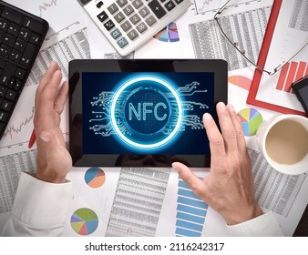 Trader man hands using digital tablet computer with near field communication hologram on screen. Mobile payment and modern technology concept. Top view.