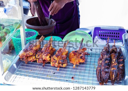Traders are cooking papaya salad and have grilled chicken on the tray. In Thailand.