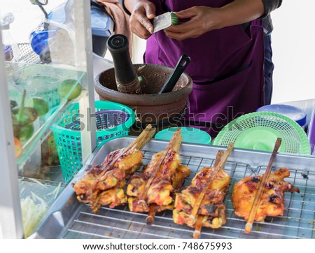 Traders are cooking papaya salad and have grilled chicken on the tray. In Thailand.