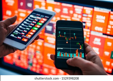 Traders or financial analysts checking the recent stock exchange trends using their smartphones. - Shutterstock ID 1529398208