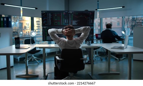 Traders working in modern large open space office. Back view of broker relaxing on chair looking at multi-screens with data - Powered by Shutterstock