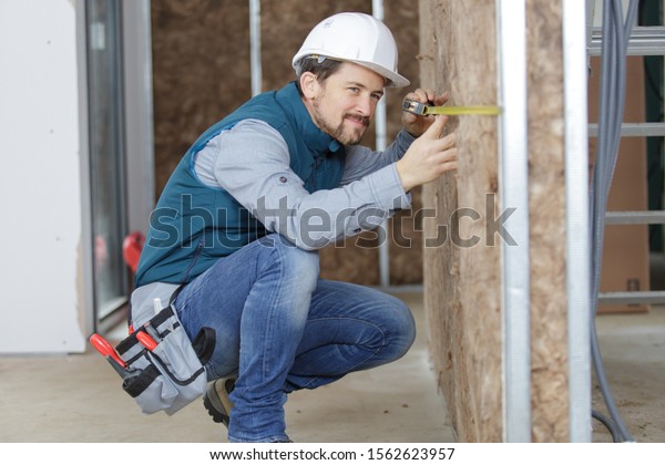 tradesman measuring\
insulated partition\
wall