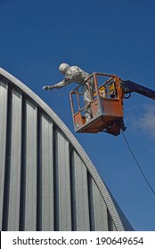 Tradesman Spray Painting The Roof Of An Industrial Building