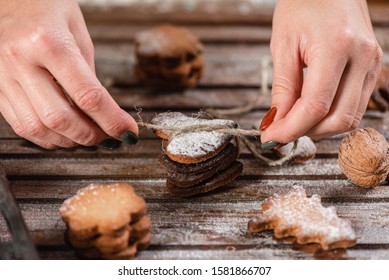 
The tradition of celebrating Christmas. A woman is packed gifts from home baking on a wooden table. Close-up.